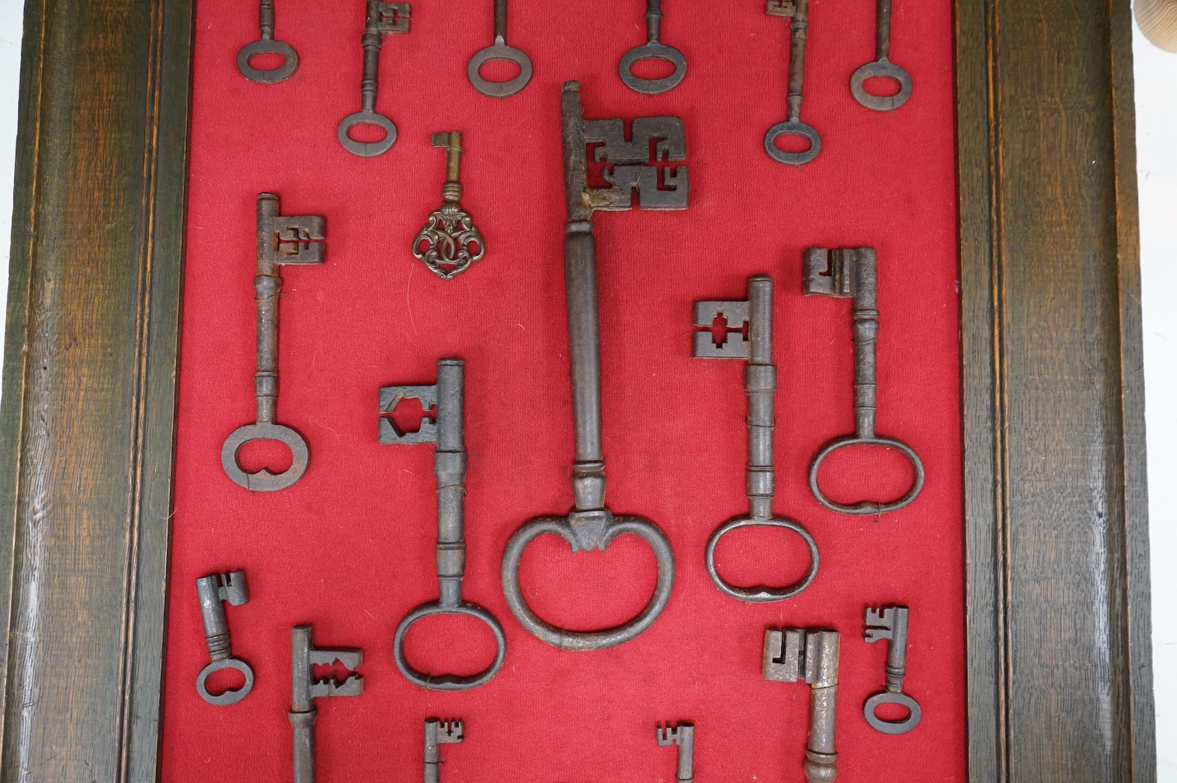 A framed collection of early antique iron keys, largest key 25cm long, board with all keys 66cm high
